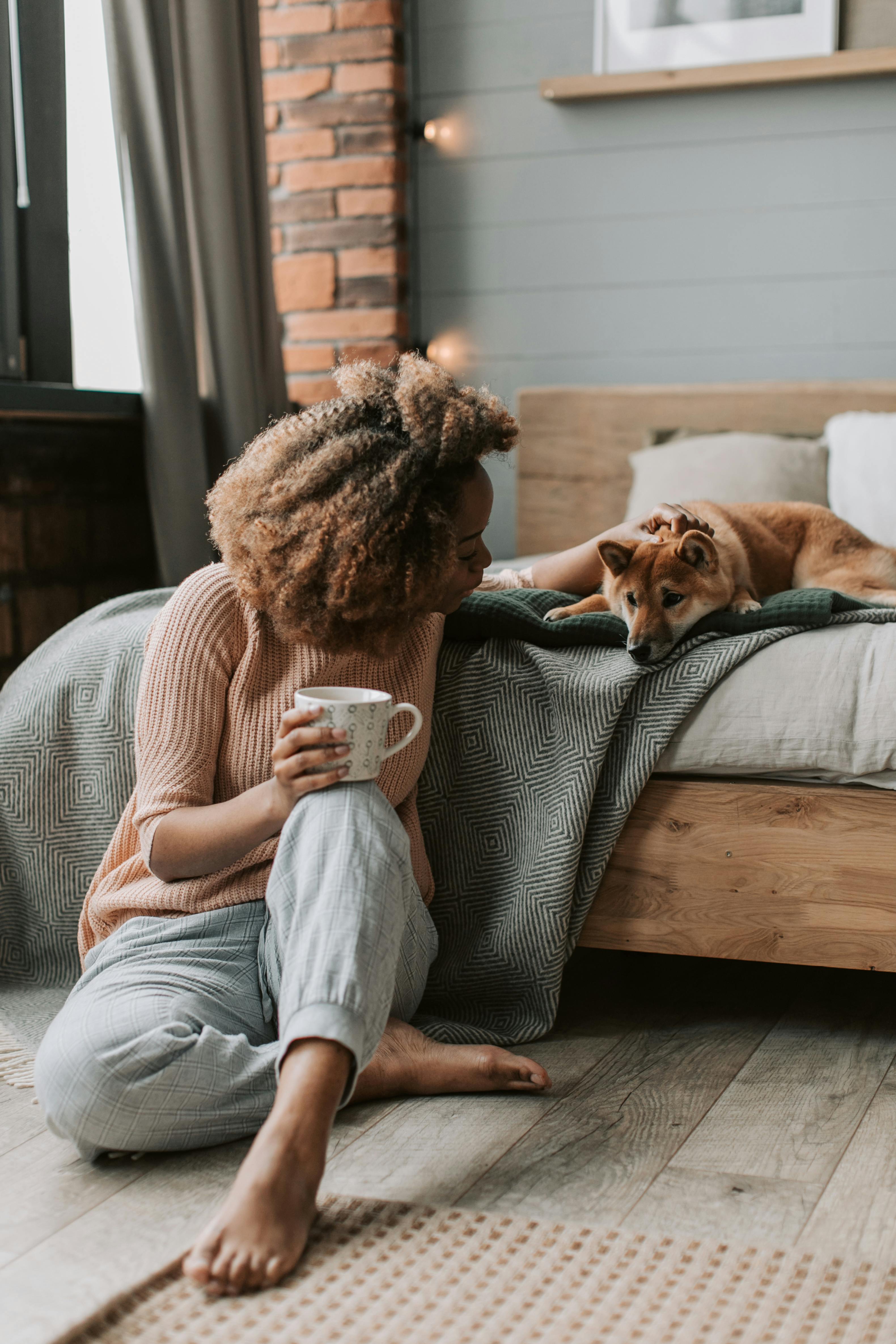 A woman enjoys a cozy moment with her dog in a stylish bedroom, perfect for relaxation.