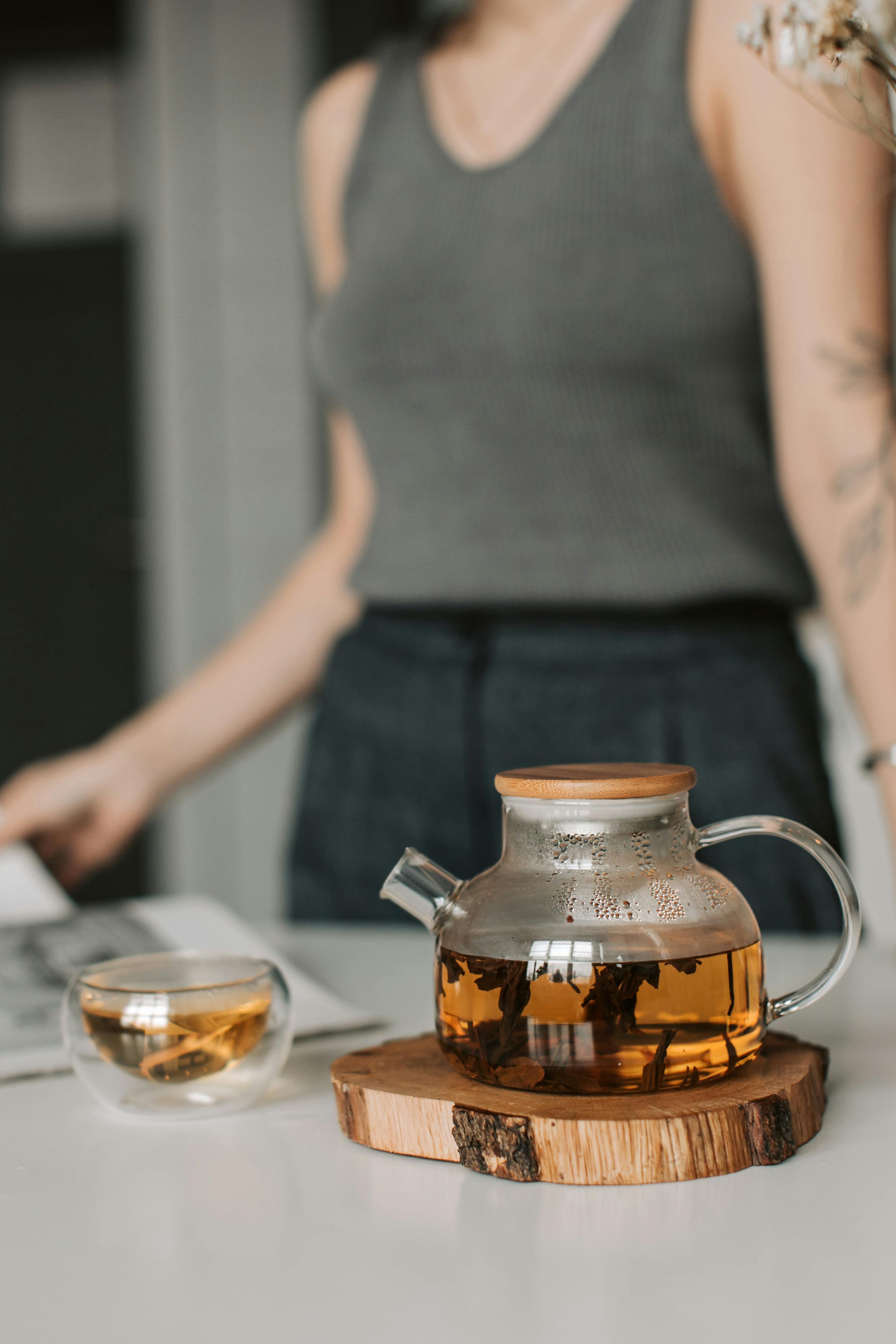 Elegant teapot and cup on wooden coaster in a chic kitchen setting.