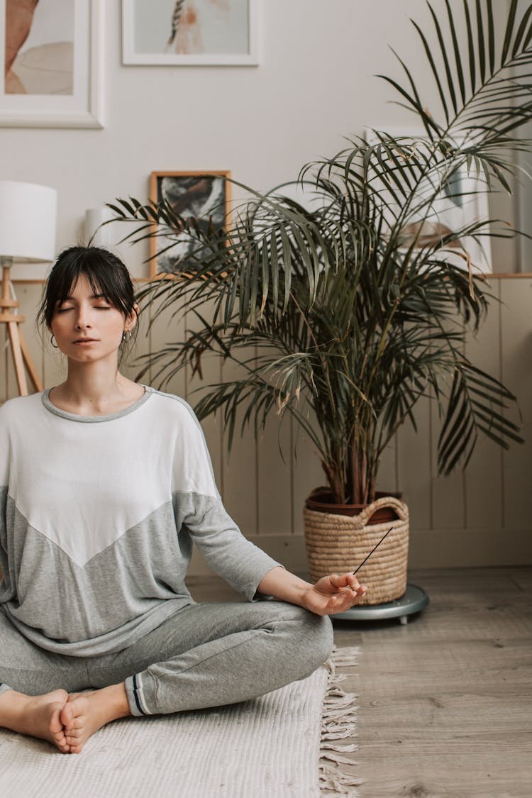 A Woman Meditating While Holding An Incense