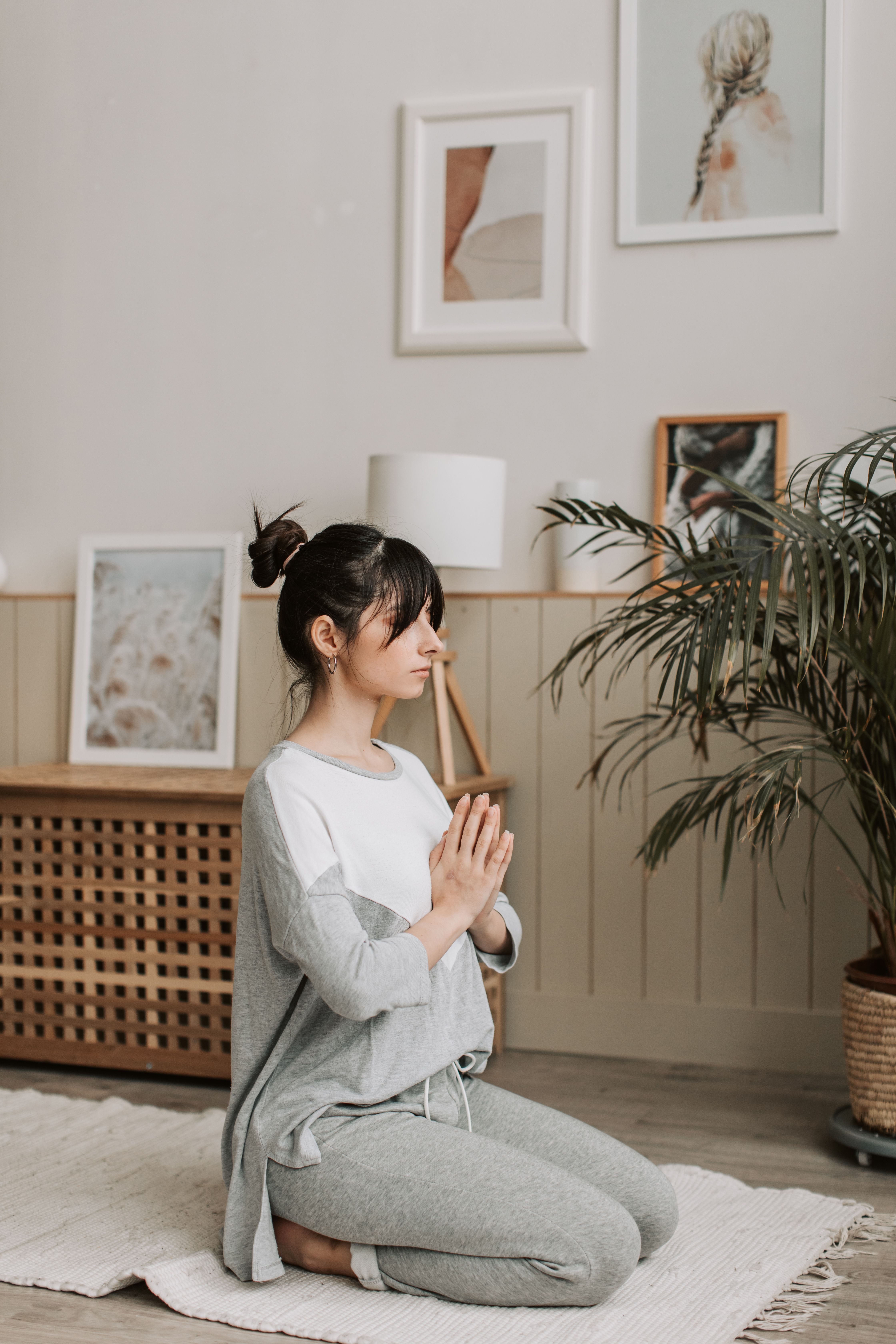 A woman meditating cross-legged indoors with her eyes closed