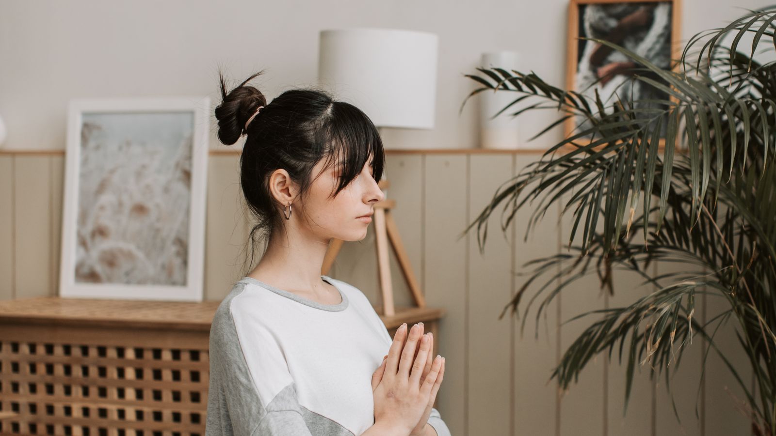 A woman meditating cross-legged indoors with her eyes closed