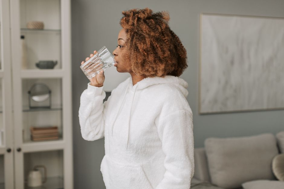 A person drinking water to stay hydrated and reduce facial puffiness A person drinking water to stay hydrated and reduce facial puffiness