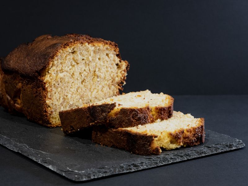 Tasty banana bread loaf with slices on a slate board, perfect for dessert or snack.