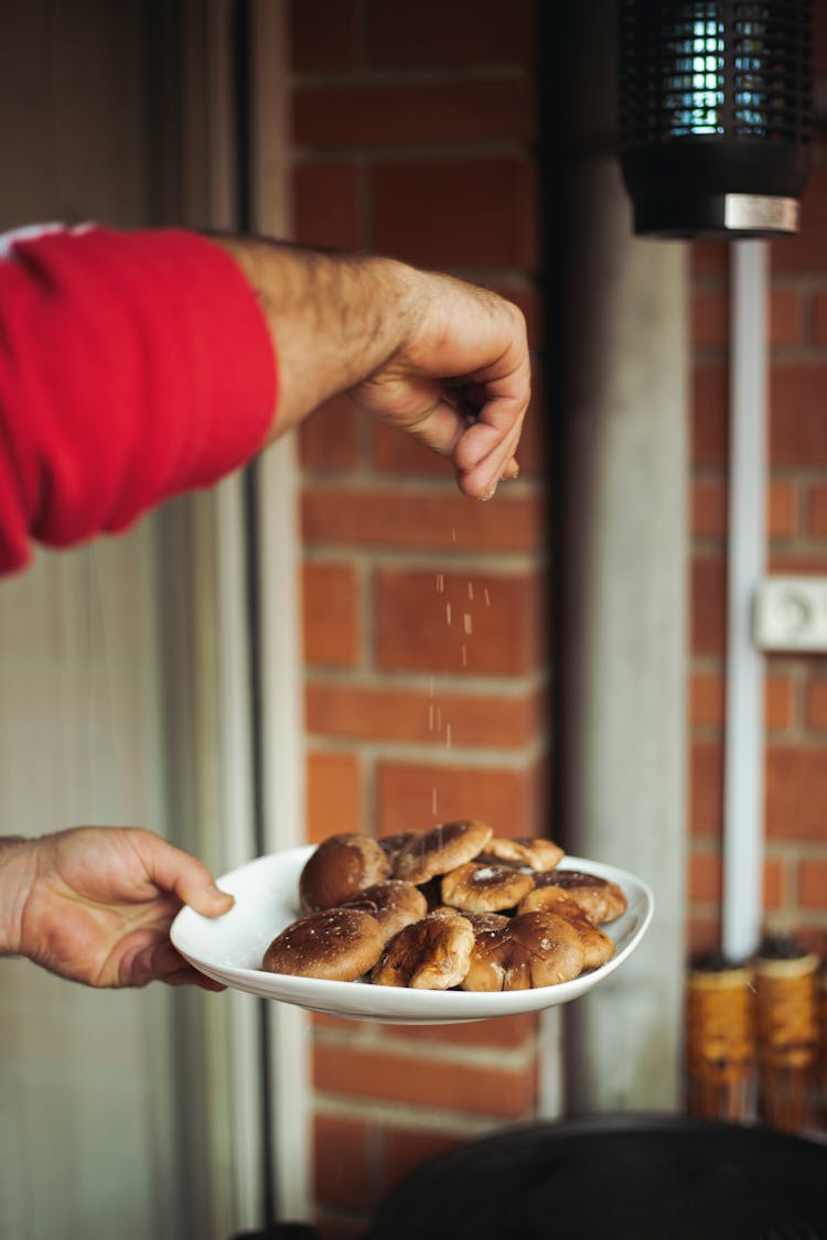 A Person Seasoning A Plate Of Food