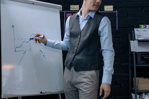 Man in Gray Vest Standing Beside a Whiteboard