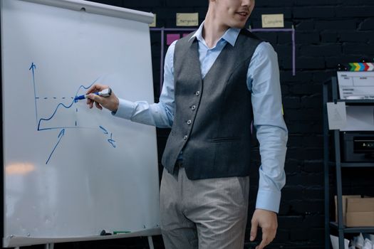 A businessman drawing a graph on a whiteboard during a presentation in an office environment.