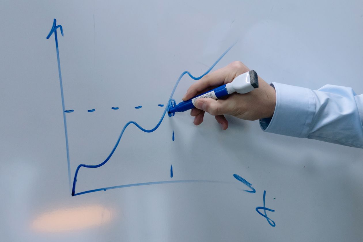 Hand drawing an upward growth graph on a whiteboard, representing the journey from zero to income during a 5-day AI challenge