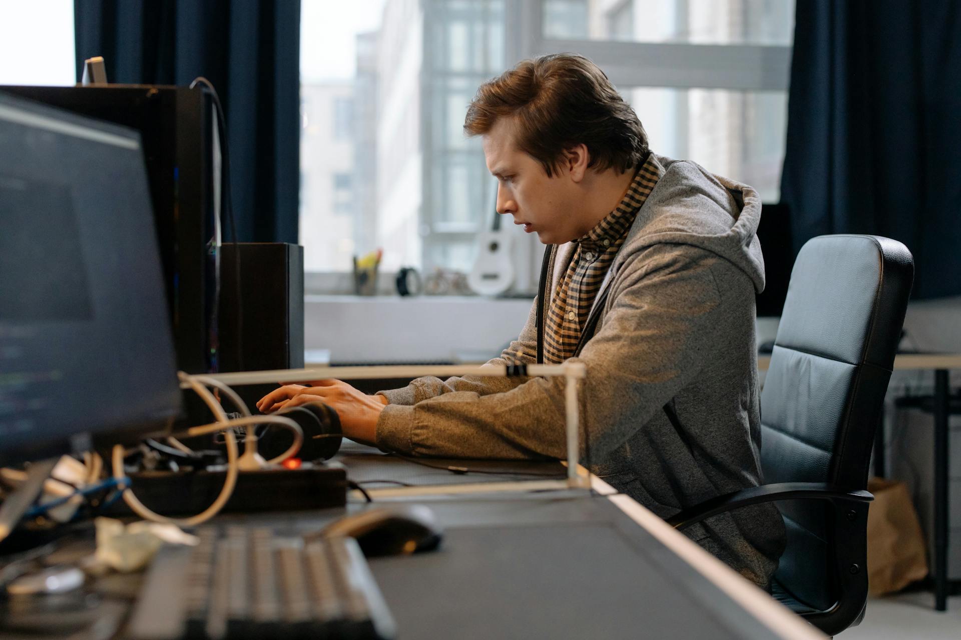 A concentrated professional working at a computer in a modern office setting.