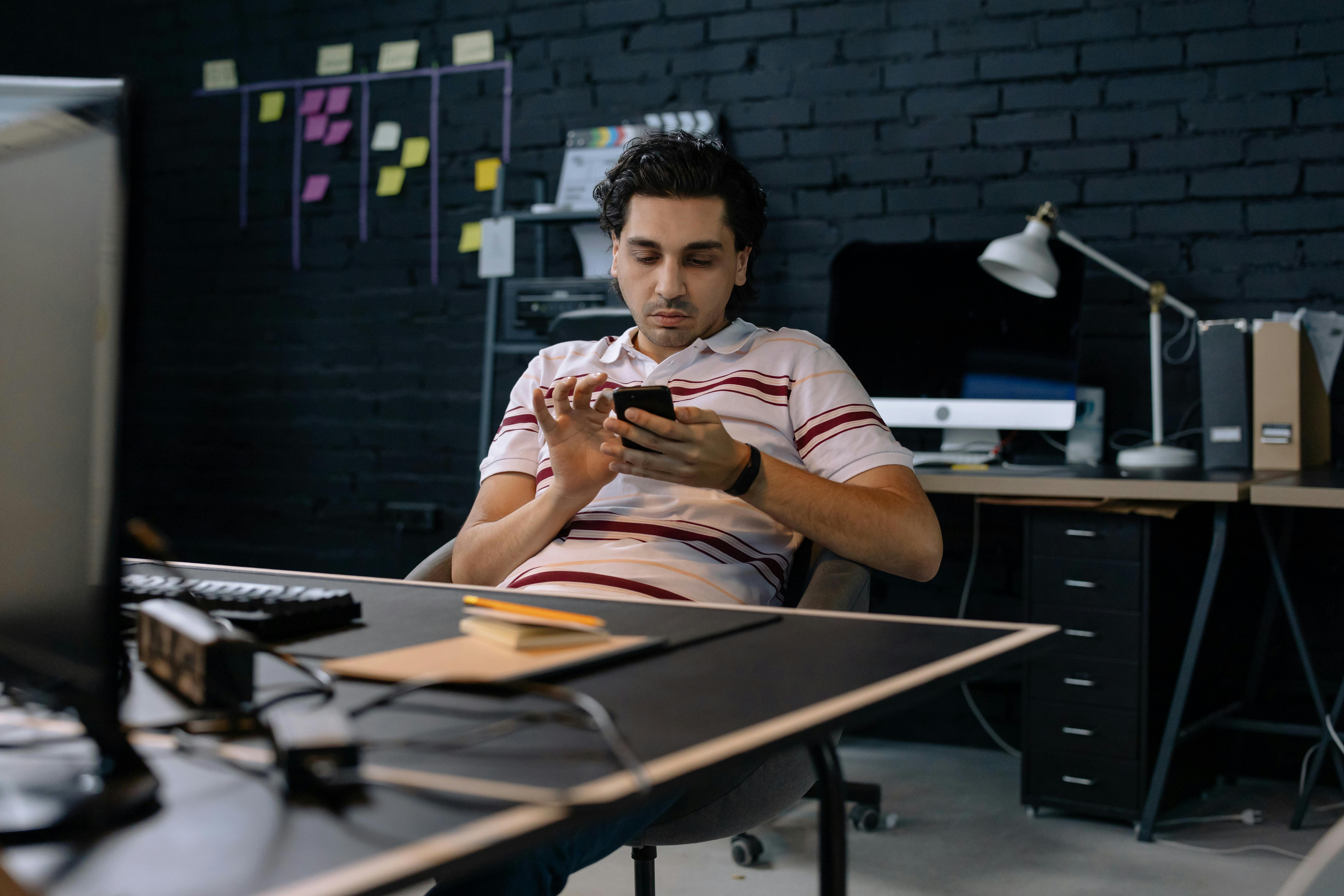 A focused businessman using a smartphone in a modern office environment.