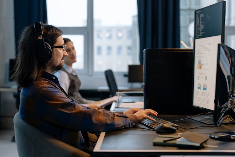 A Man Sitting At The Table While Using Computer