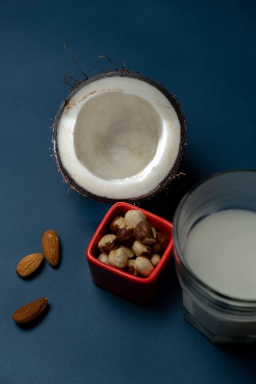 Free A vertical shot of almonds, macadamia nuts, coconut, and plant-based milk on a dark background. Stock Photo