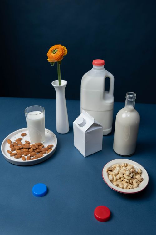 Free A still life of nut milk varieties with almonds, cashews, and a single flower in a vase. Stock Photo