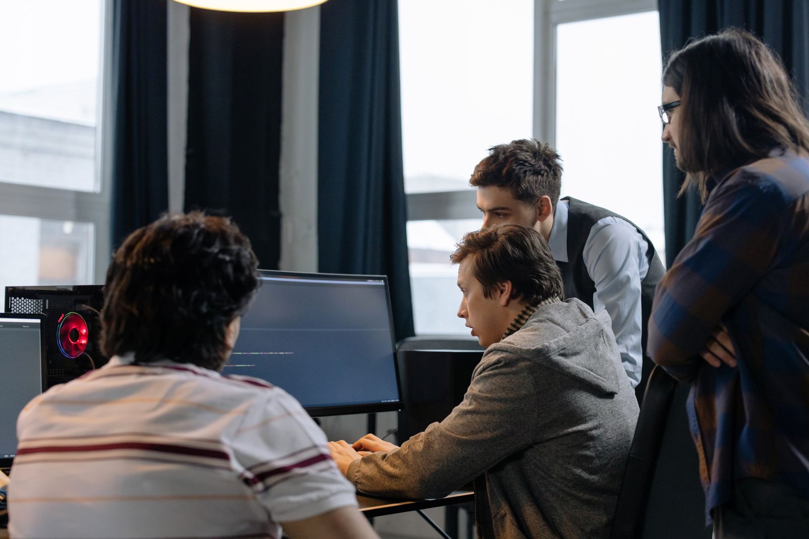 Four engineers gathered around one screen reading through a change together. Photo by cottonbro studio on Pexels.