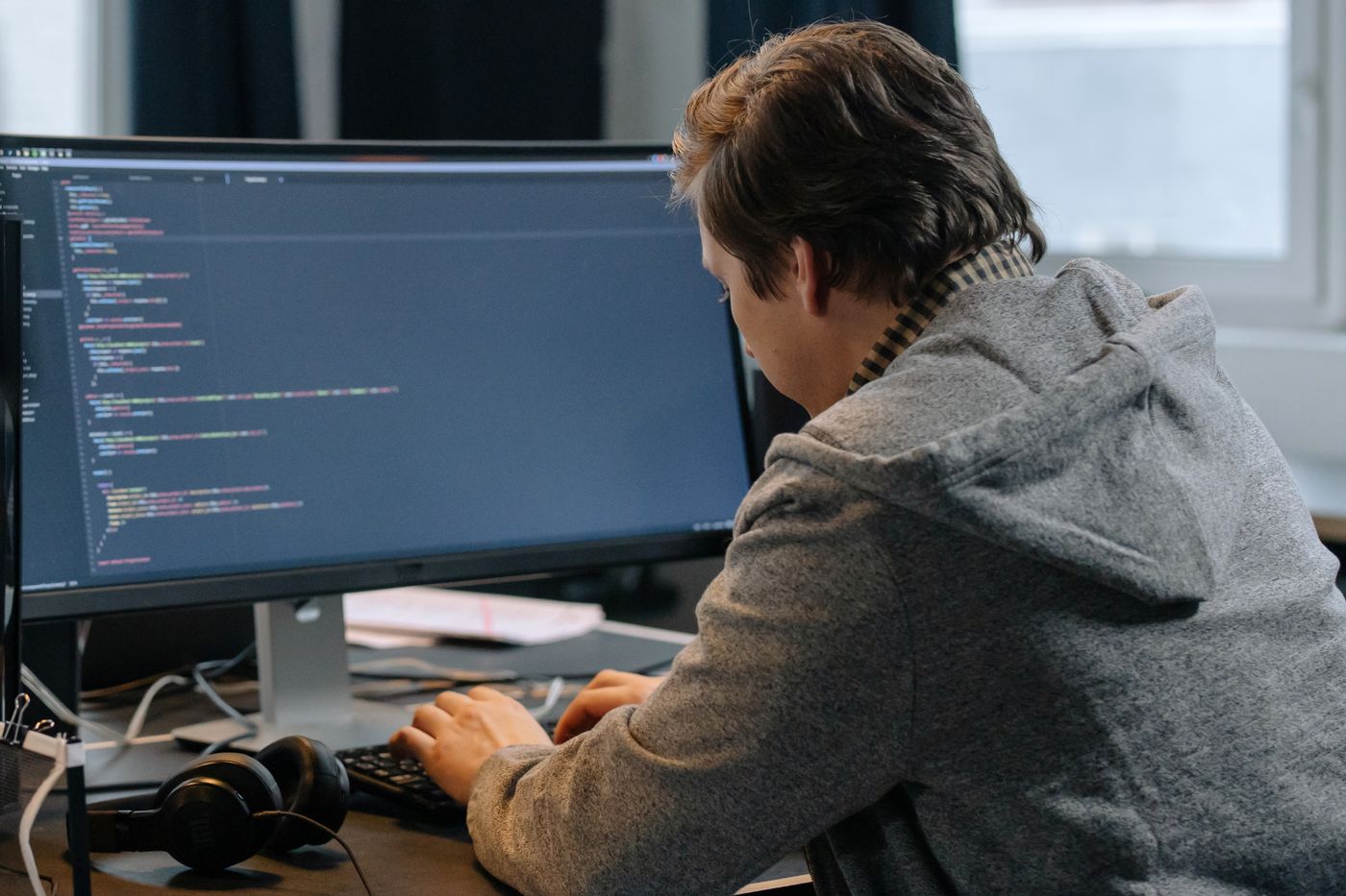 Web developer working on laptop with multiple code screens