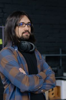 Portrait of a young IT professional with headphones, confidently posing in an office setting.