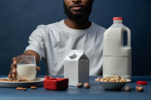 Man Sitting at Table Holding a Glass of Milk