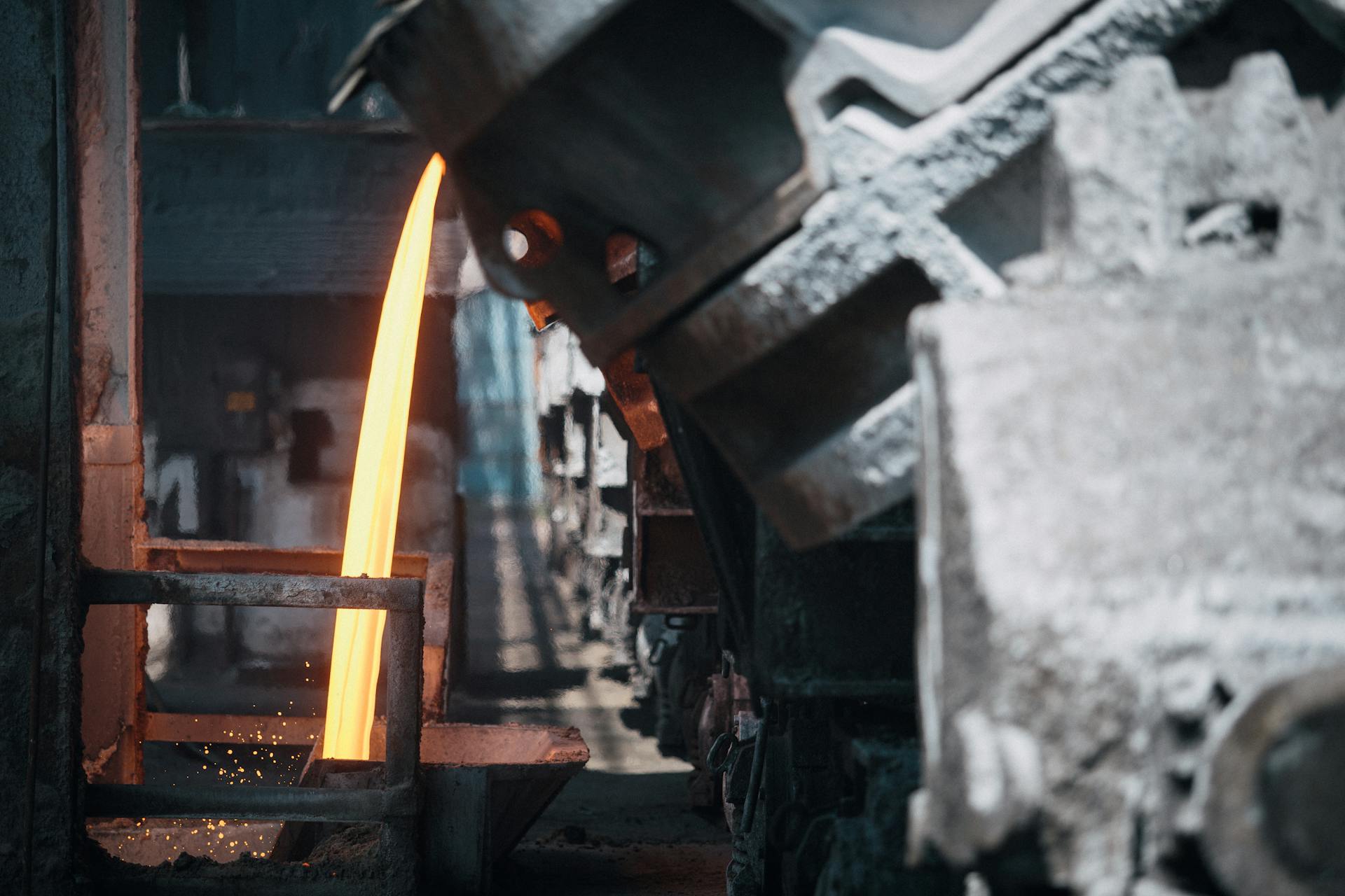 A powerful image of molten metal pouring in a heavy industry steel mill setting.