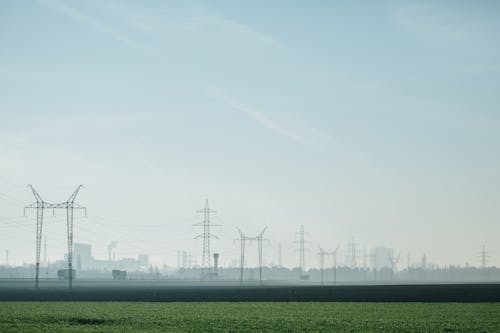 Green Grass Field with Electric Towers Under Blue Sky