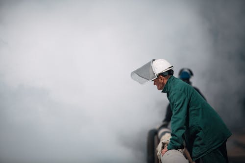 A Man Wearing Protective Clothing Standing Near the Smoke