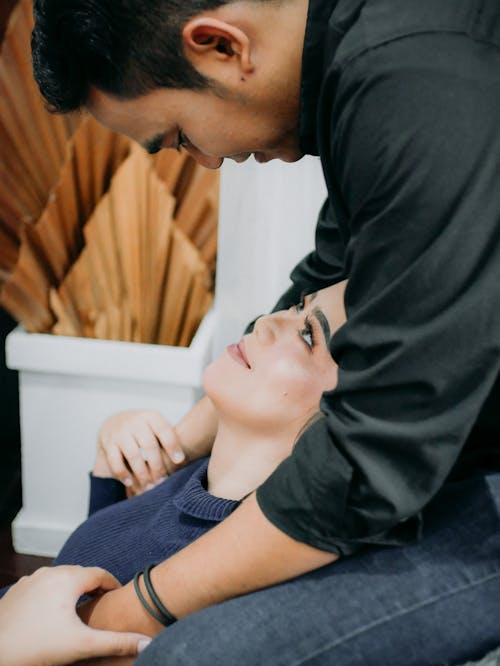 Free Man Leaning Over and Embracing a Woman Sitting on the Floor  Stock Photo