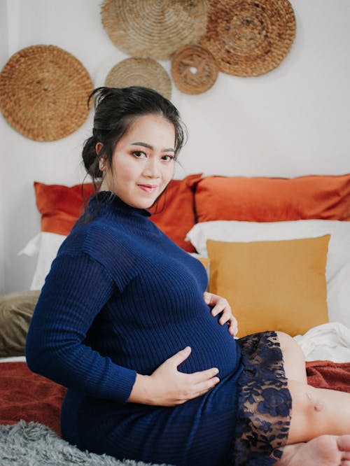 Free A Pregnant Woman Sitting on a Bed  Stock Photo