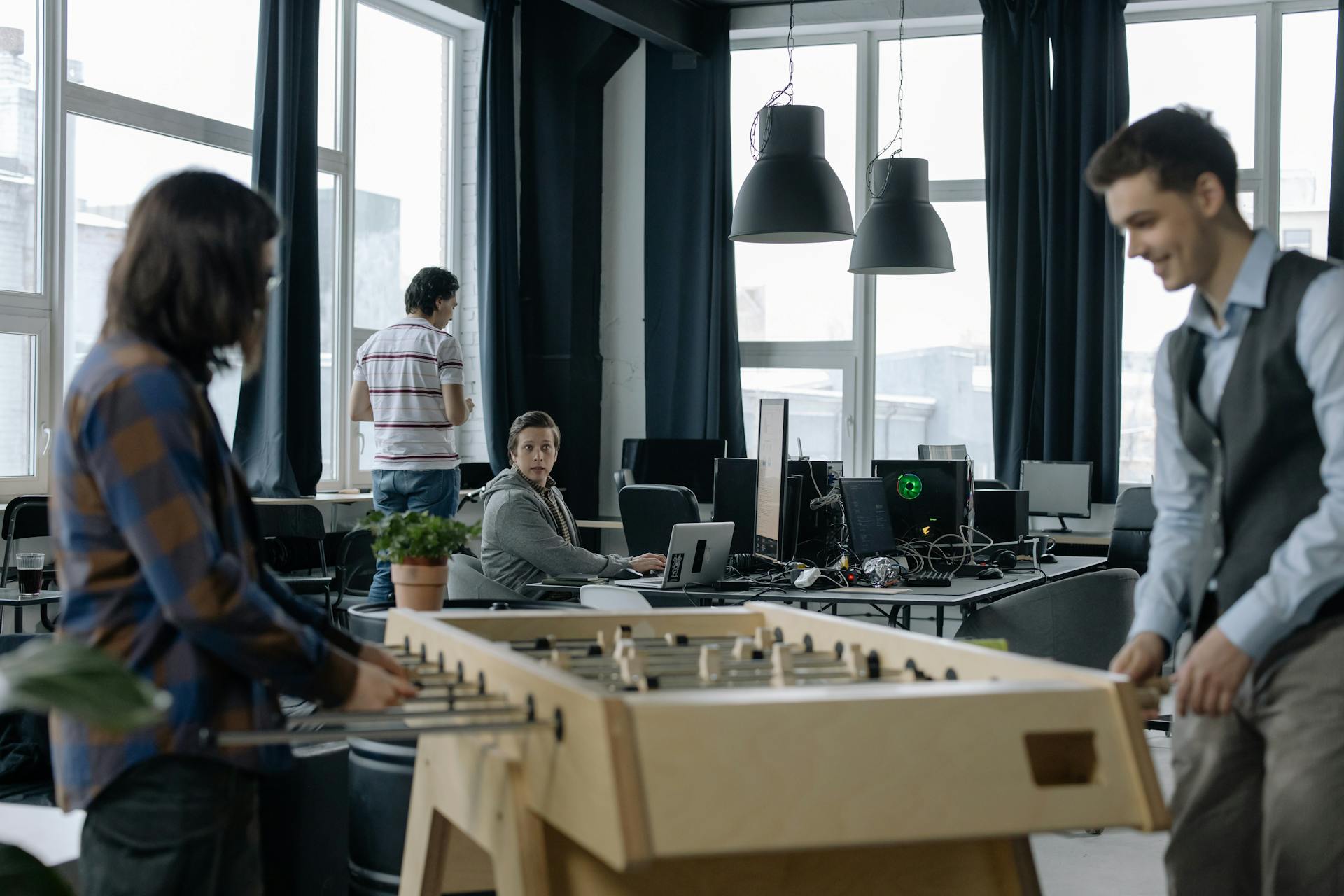 A modern office environment featuring a foosball table with employees engaging in teamwork.