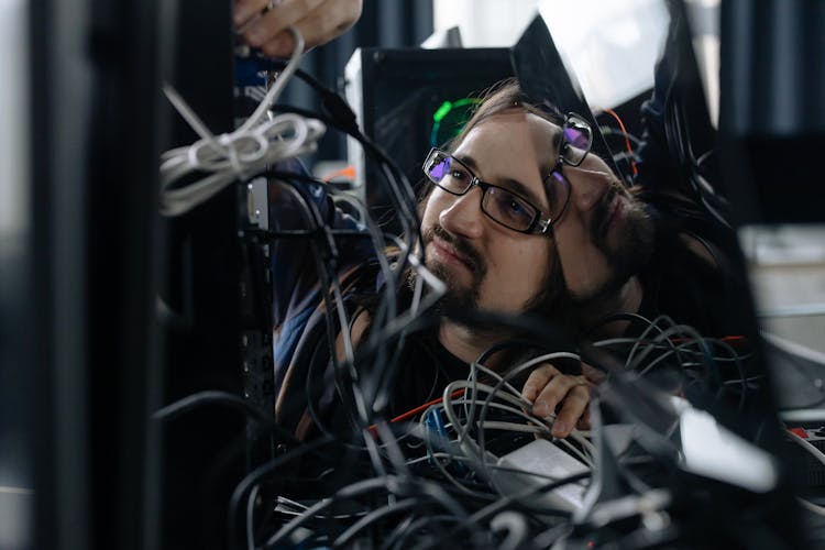 Employee Working Through The Tangle Of Cables Behind The Computer