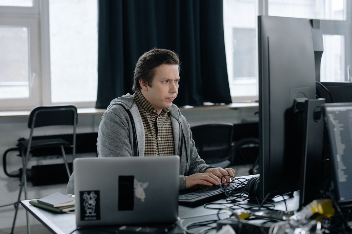 A programmer working at a desk with dual monitors