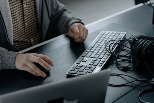 Person in Gray Jacket Sitting in Front of a Computer Keyboard