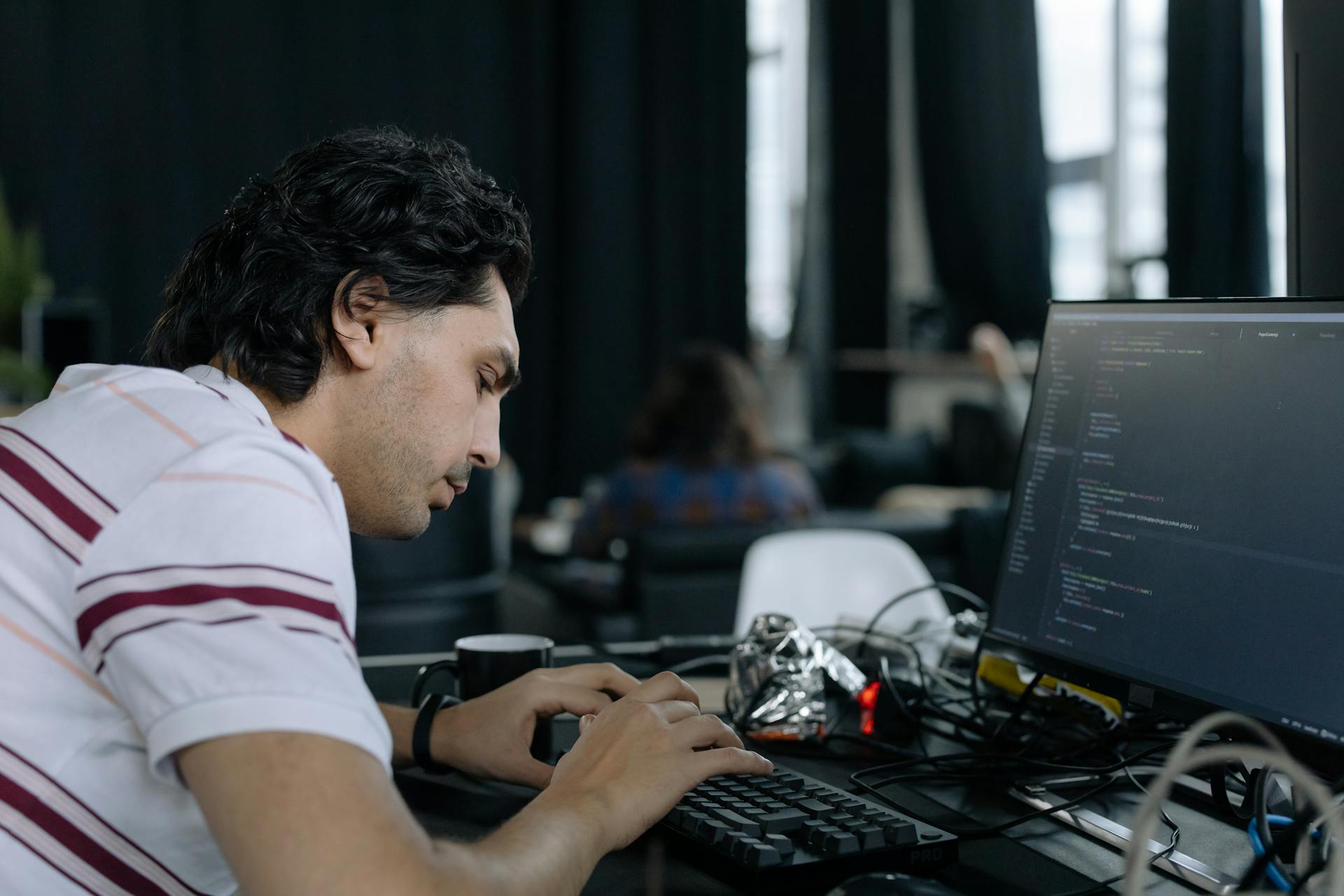 A coder intensely typing at a workstation in a contemporary office setup.