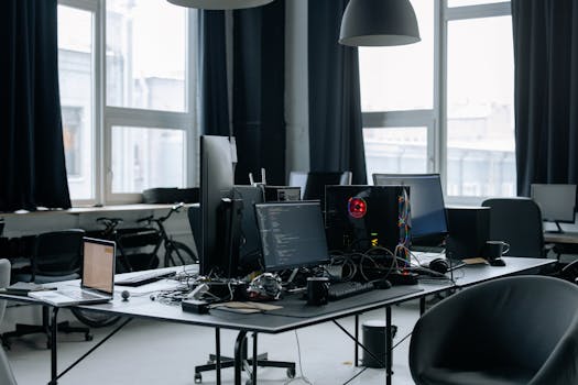 Contemporary workspace featuring computers, coding screens, and office essentials in a tech environment.