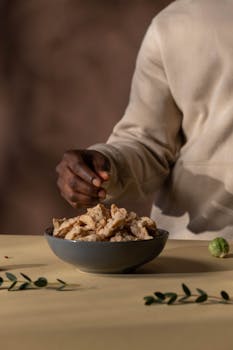 A person preparing a vegan meal with soy meat in a bowl, featuring a minimalist setting.