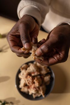 Close-up of hands shredding cooked soy meat in a bowl, perfect for food prep visuals.