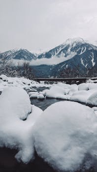Captivating snow-covered mountain scene with icy river, showcasing nature's winter beauty.