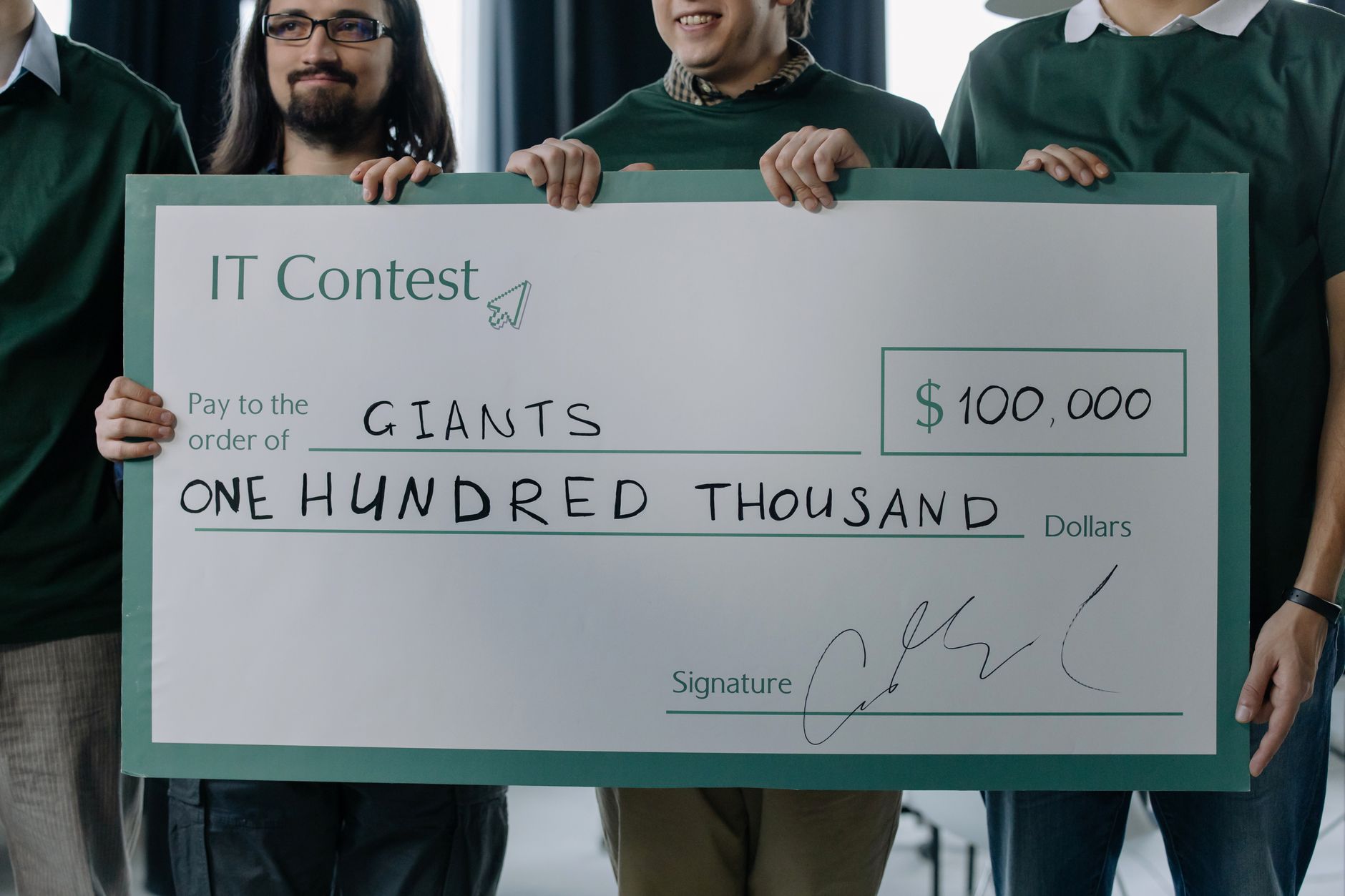 Group of men holding a $100,000 prize check after winning an IT contest.