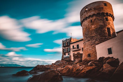 Scenic view of an ancient tower and rocky coastline in Tuscany, Italy at twilight.