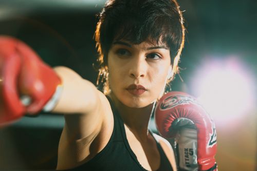 Free Female boxer practicing intense punching technique indoors with strong determination. Stock Photo