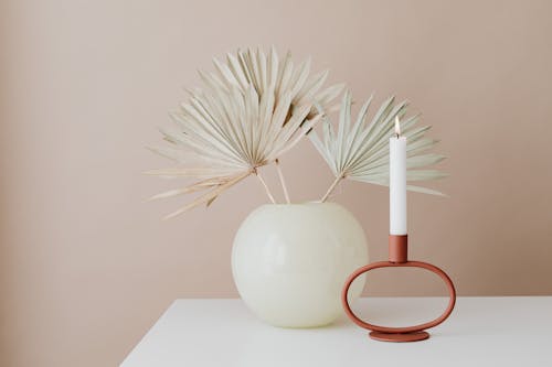 Dry Palm Leaves in a Ball Shaped Vase and a Burning Vertical Candle 
