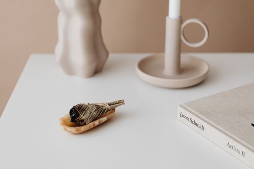 Free Elegant minimalist setup featuring a sage bundle, candle, and decorative objects on a white surface. Stock Photo