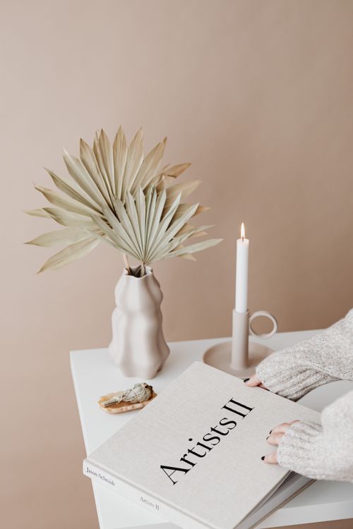 Free Elegant minimalist decor with dried palm, candle, and book, creating a warm and cozy atmosphere. Stock Photo