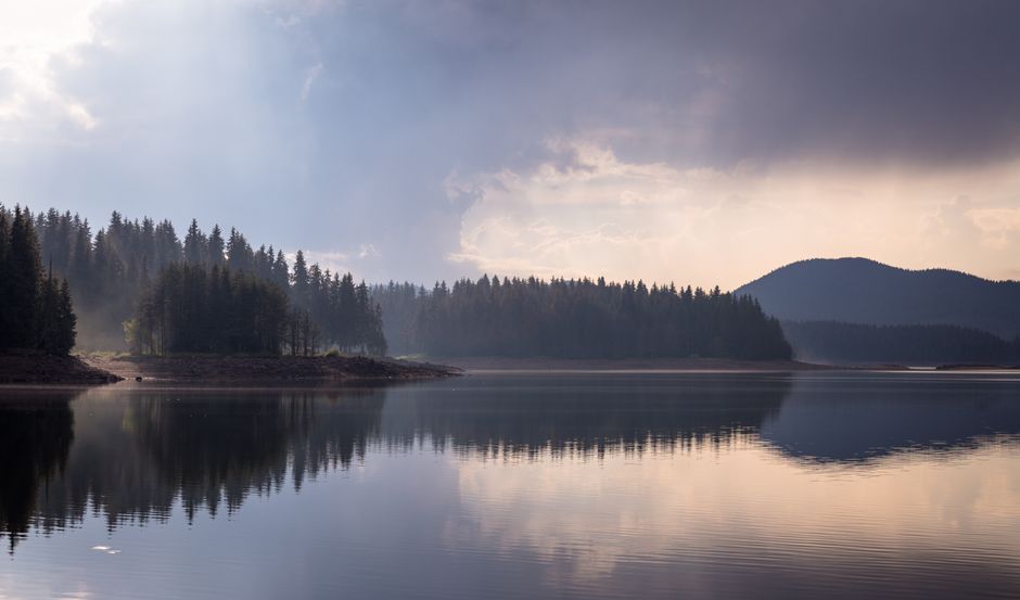 A serene nature scene showing a calm lake reflecting the sky, symbolizing the reflective and peaceful inner world of a Pisces.