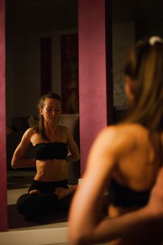 A woman practicing yoga indoors, mirrored in a peaceful setting.
