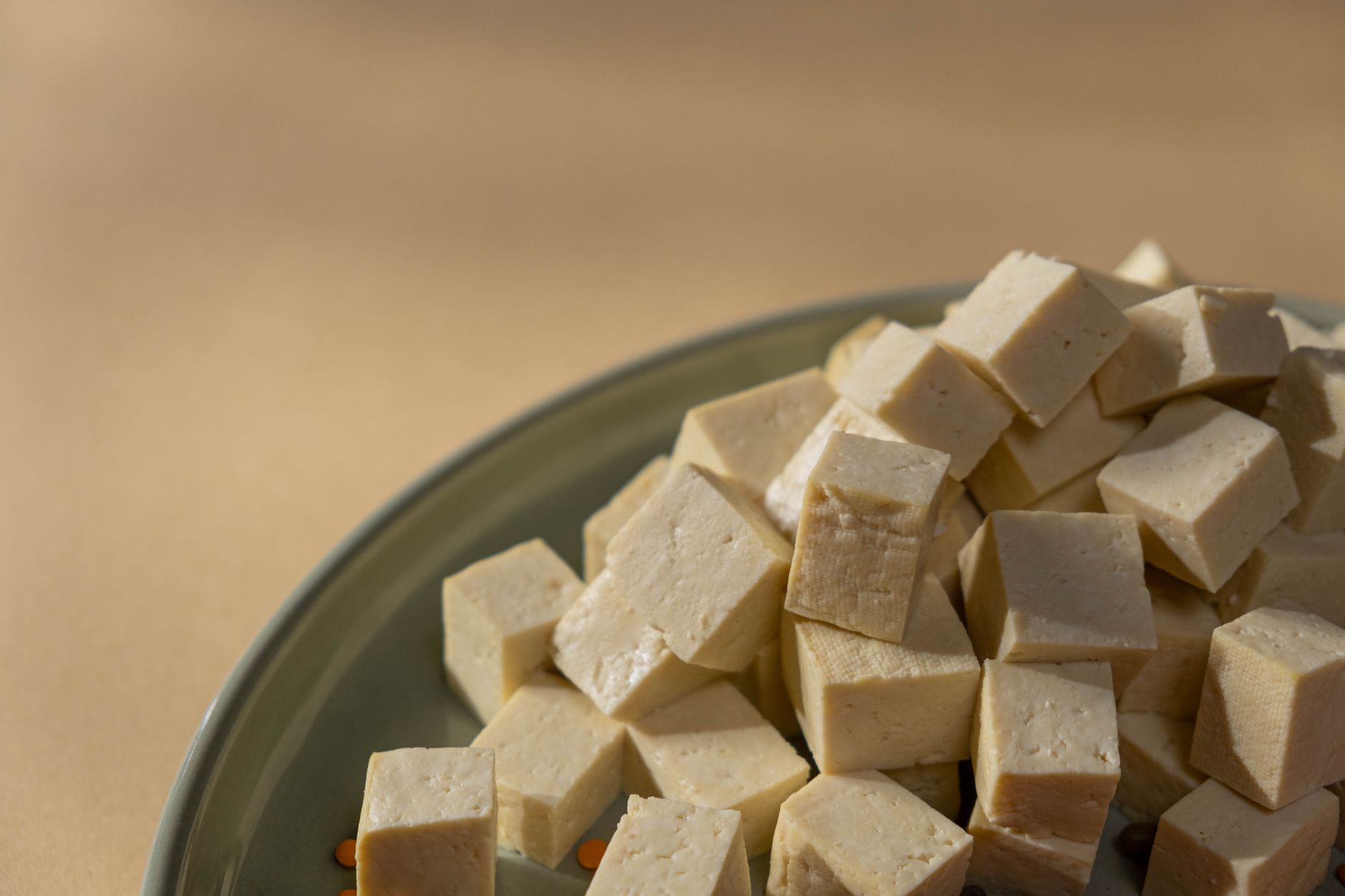 Close-up view of raw cubed tofu on a green plate, ideal for healthy recipes.