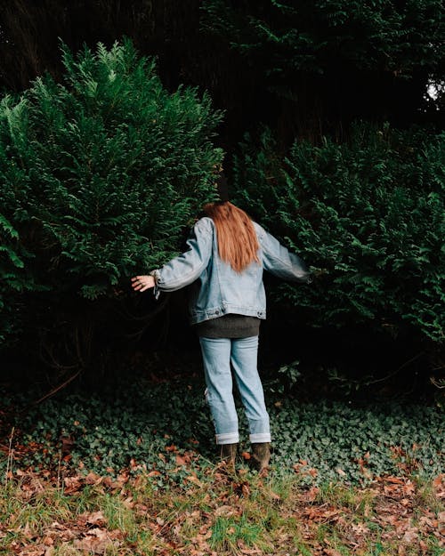 Woman standing between green bushes in park