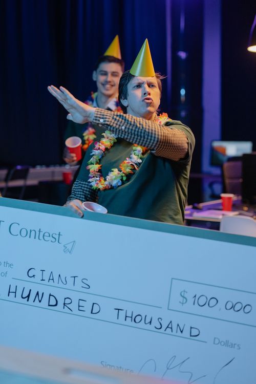 Free Two men celebrating a contest win with a giant check indoors. Stock Photo
