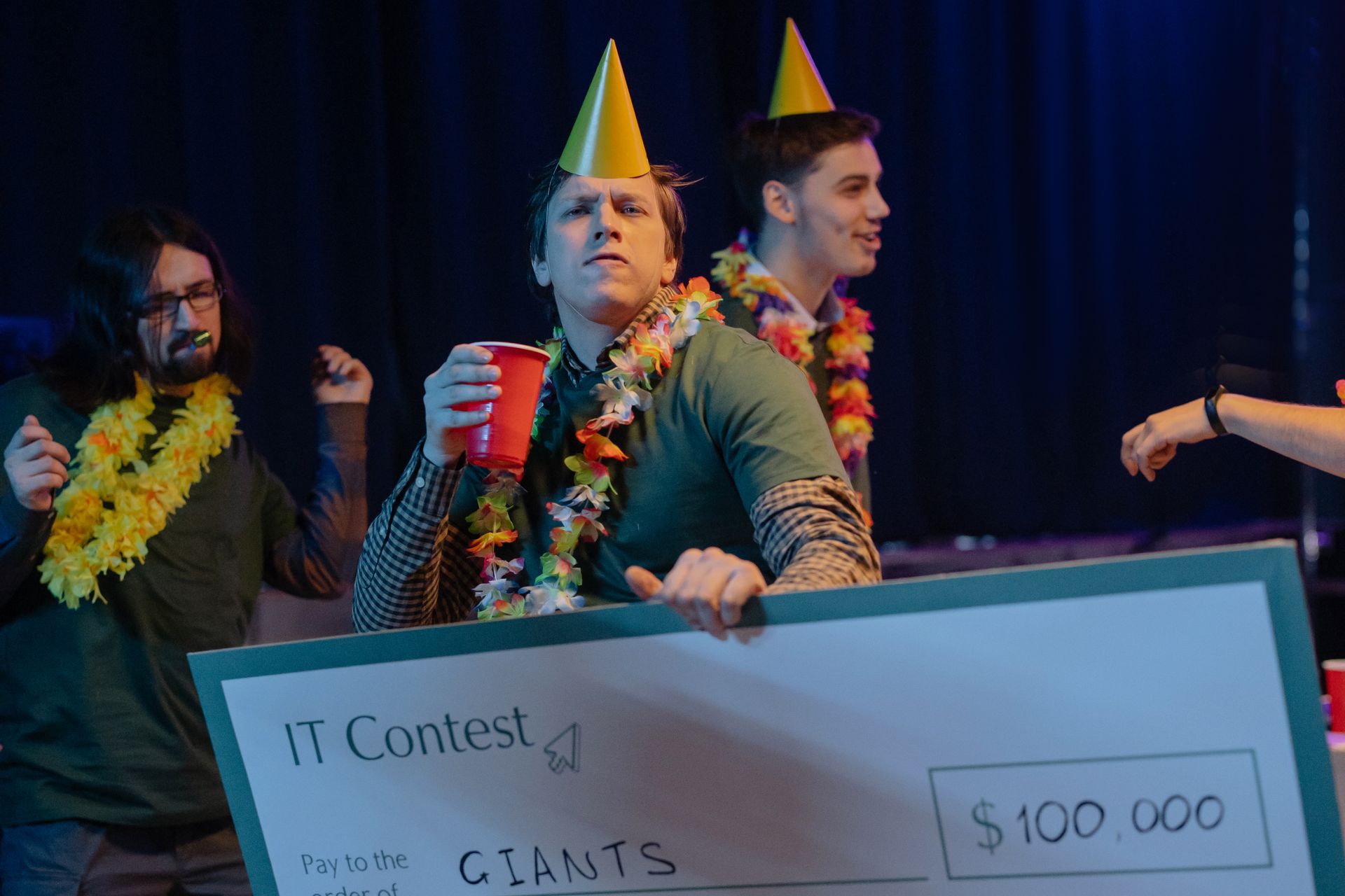 Three men celebrating a $100,000 IT contest win with drinks and decorations.