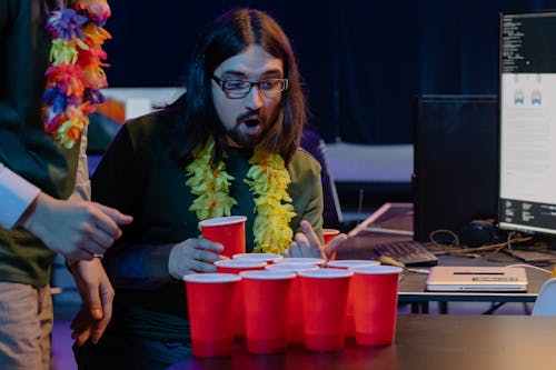 Amazed Long Haired Man Looking at Red Disposable Cups with Drinks