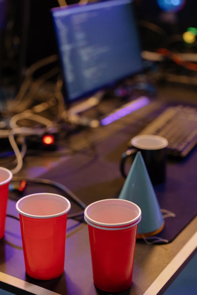 Red Disposal Cups And Party Hat Standing On A Computer Desk