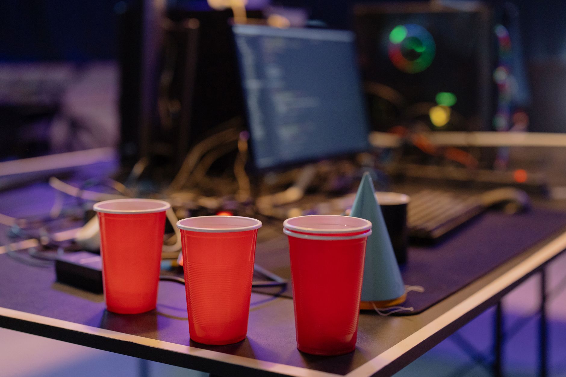 Red cups and a birthday hat on a desk in a modern office party setting.