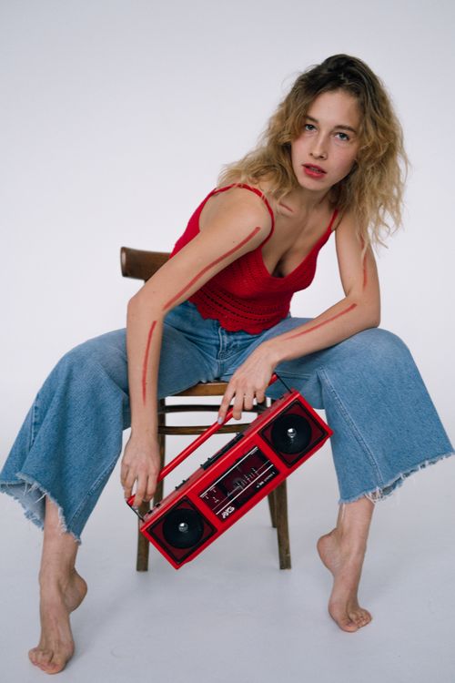 Free Stylish young woman in jeans and red top holding a retro boombox. Stock Photo
